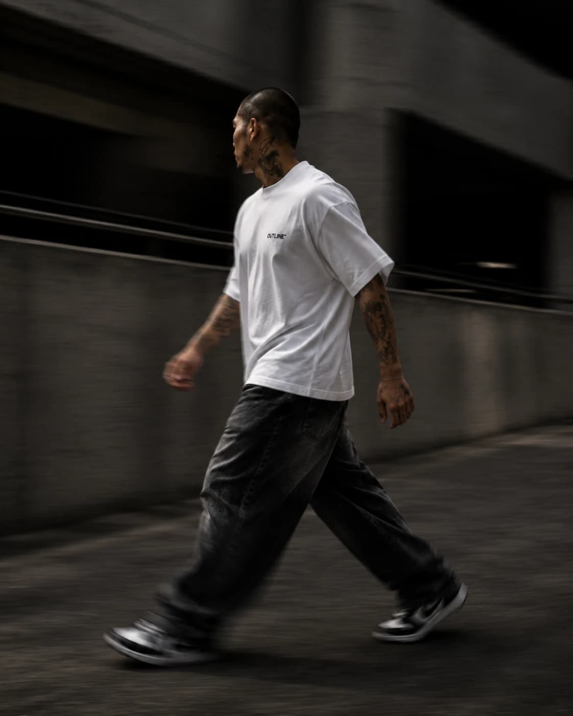 Model walking in motion blur, white OUTLINE tee and washed denim